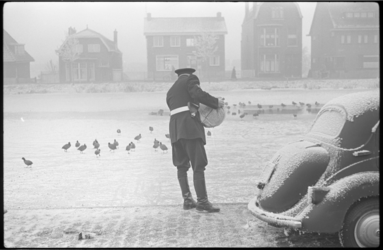 3040-2 Weersomstandighedenfoto van politieagent die dieren op bevroren water van de Rotte van voedsel voorziet.
