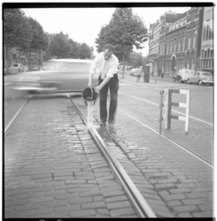 3408 In verband met door de hitte uitgezette tramrails giet een man water in de rails op Mathenesserlaan.