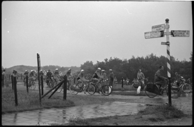 4332-2 Deelnemers aan de (natte) Tour van Drie passeren op 300 meter van het Kruiniger Gors een wegwijzer.