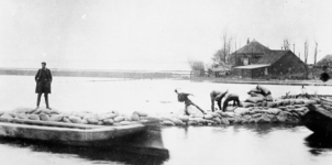 1975-565 Bezoek van autoriteiten aan de dijkdoorbraak in de Noordkethelpolder te Schiedam. Leggen van zandzakken op de ...